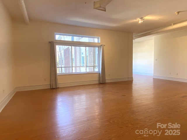 spare room with wood finished floors and baseboards