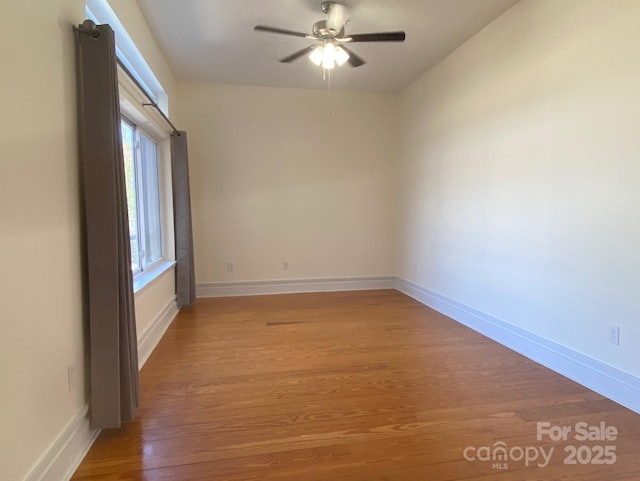 spare room with ceiling fan, light wood finished floors, and baseboards