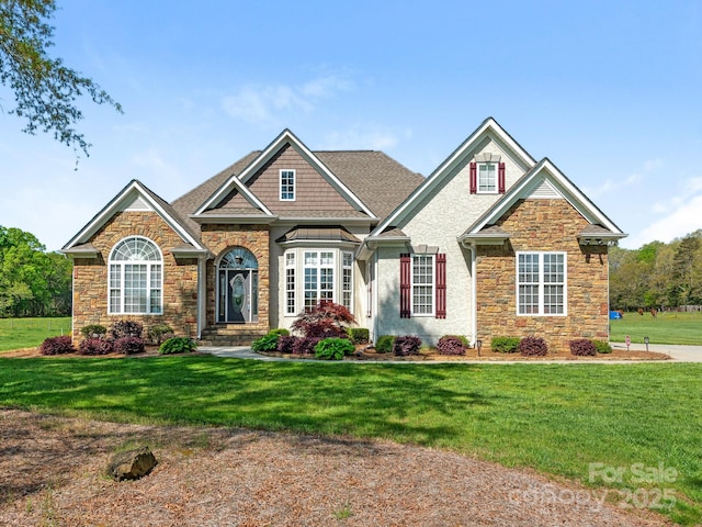 craftsman-style home with stone siding, a front lawn, and a shingled roof