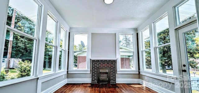 unfurnished sunroom with a wood stove and a healthy amount of sunlight