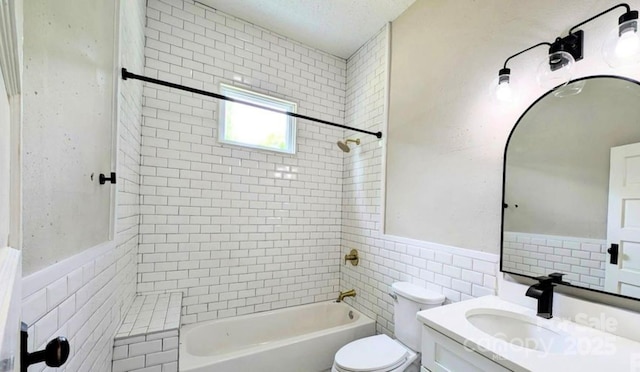 bathroom with a wainscoted wall, tile walls, toilet, washtub / shower combination, and vanity