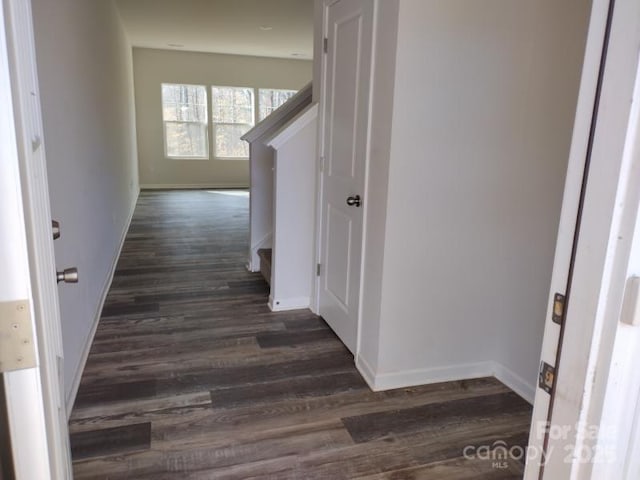 corridor with dark wood-style floors, stairs, and baseboards