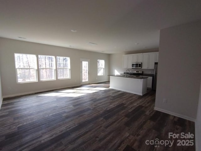 unfurnished living room with baseboards, dark wood finished floors, and a sink