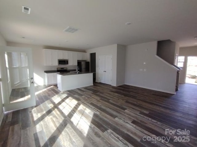 kitchen featuring stainless steel appliances, visible vents, dark wood-type flooring, open floor plan, and white cabinets