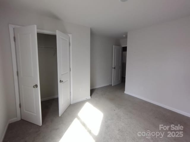 unfurnished bedroom featuring carpet floors, a closet, and baseboards