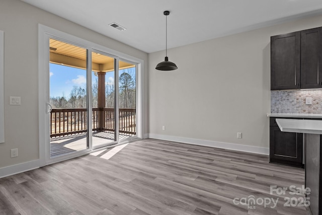 unfurnished dining area featuring baseboards, visible vents, and light wood finished floors