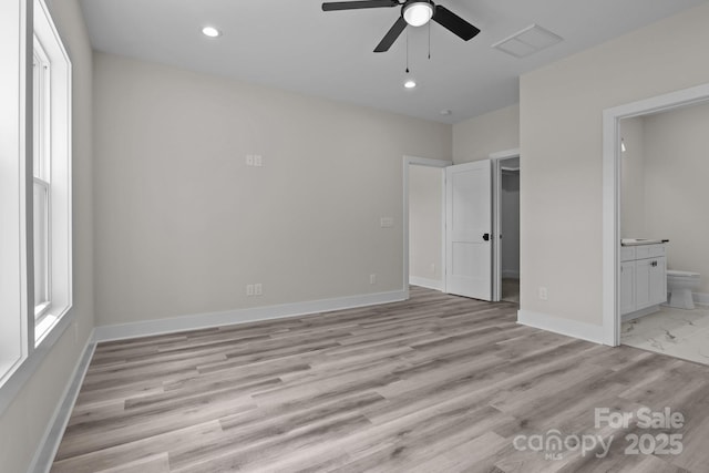 unfurnished bedroom featuring multiple windows, connected bathroom, visible vents, and baseboards