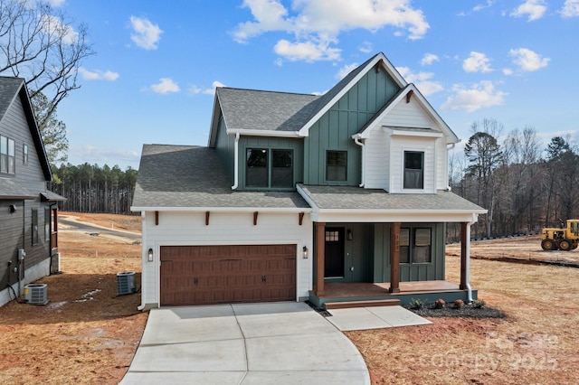 modern farmhouse featuring board and batten siding, cooling unit, covered porch, and driveway