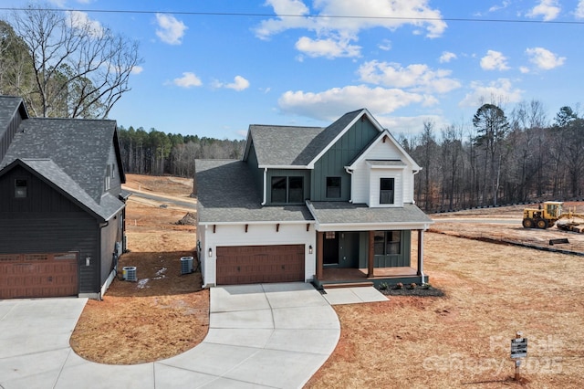 modern farmhouse featuring central air condition unit, a porch, concrete driveway, board and batten siding, and a garage