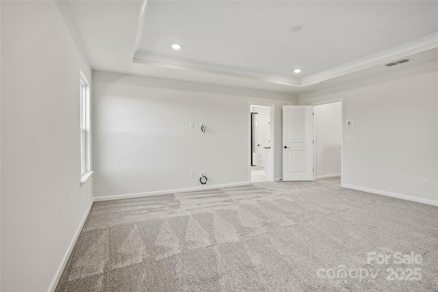 empty room with carpet, baseboards, visible vents, and a raised ceiling