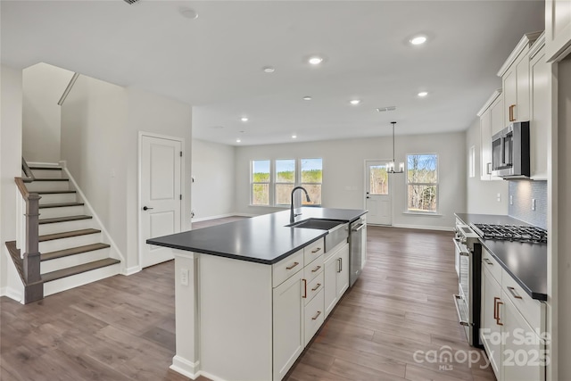 13729 Roderick Dr Unit 188, Huntersville, NC 28078 - kitchen with dark countertops, a kitchen island with sink, appliances with stainless steel finishes, a sink, and wood finished floors