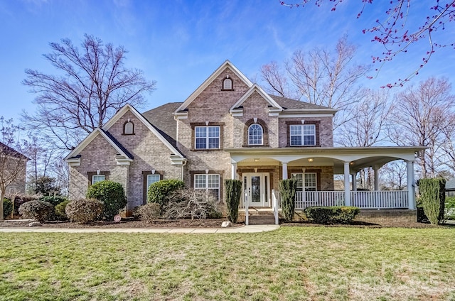 view of front facade with covered porch, a front yard, and brick siding