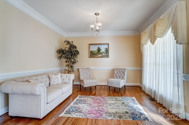 living area with ornamental molding, wood finished floors, visible vents, and a notable chandelier