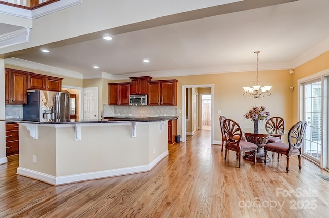 kitchen with ornamental molding, a kitchen breakfast bar, stainless steel appliances, light wood-type flooring, and a chandelier