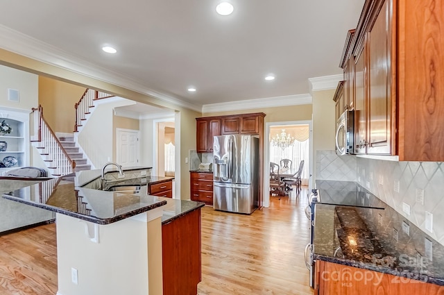 kitchen featuring appliances with stainless steel finishes, a sink, light wood-style flooring, and a breakfast bar area