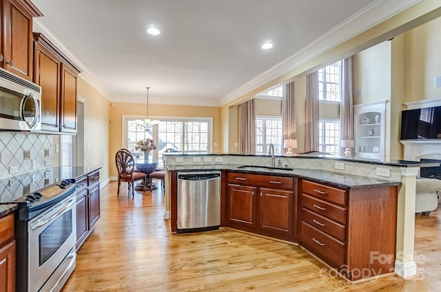 kitchen featuring light wood-style flooring, appliances with stainless steel finishes, an inviting chandelier, crown molding, and a sink