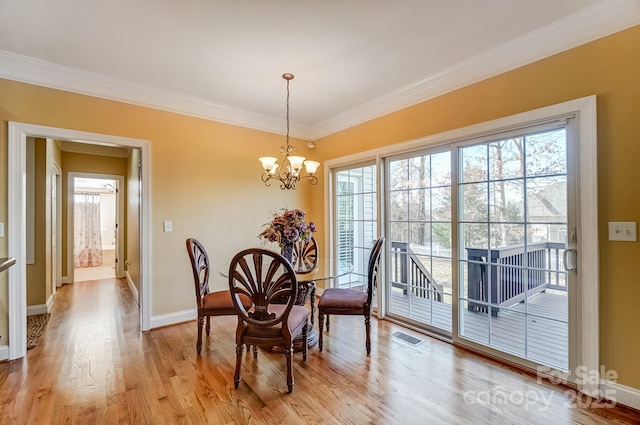 dining area featuring a notable chandelier, visible vents, baseboards, ornamental molding, and light wood-type flooring