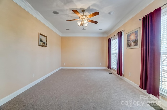 unfurnished room with crown molding, light colored carpet, visible vents, ceiling fan, and baseboards