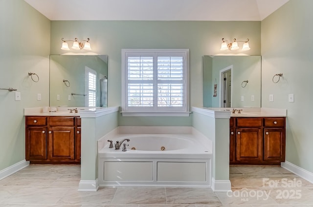 bathroom with a jetted tub, two vanities, and a sink