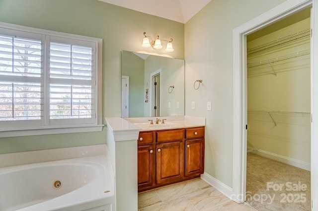 full bath featuring a jetted tub, a spacious closet, baseboards, and vanity