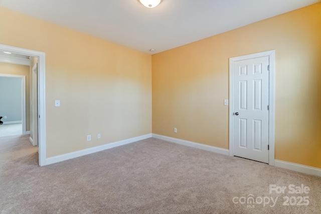 empty room featuring carpet and baseboards