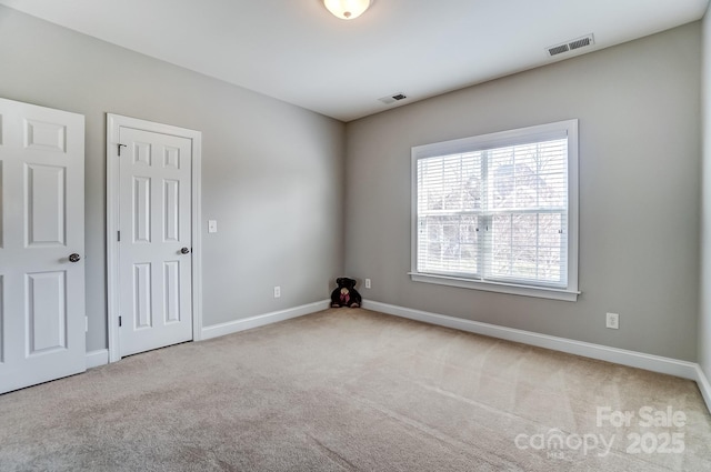 unfurnished room with baseboards, visible vents, and carpet flooring