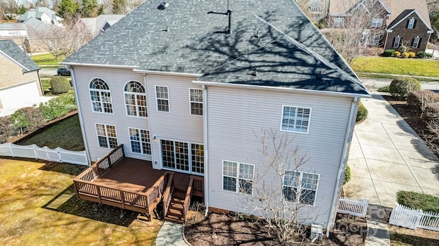 rear view of house featuring a shingled roof, fence, a lawn, and a wooden deck