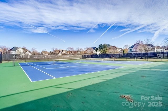 view of tennis court featuring fence and a residential view