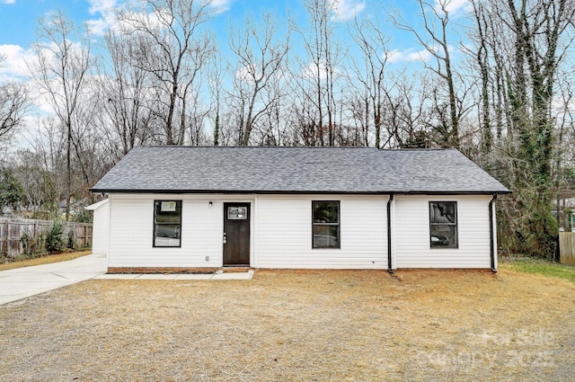 single story home featuring a shingled roof, a front lawn, and fence