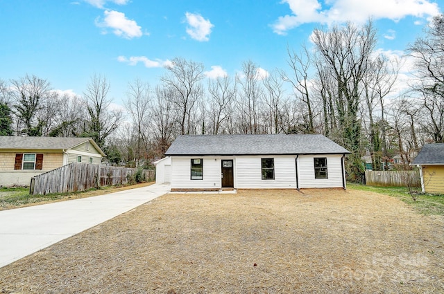 ranch-style home featuring driveway, a shingled roof, and fence