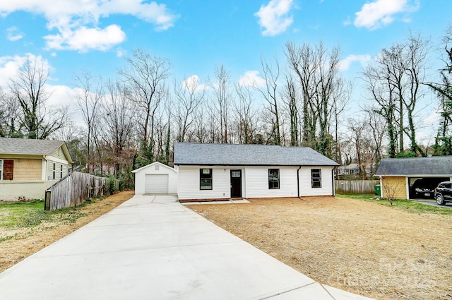 ranch-style home with driveway, a shingled roof, a detached garage, an outbuilding, and fence