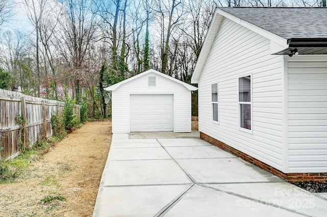 detached garage with concrete driveway and fence