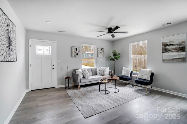 living area featuring wood finished floors, visible vents, and baseboards