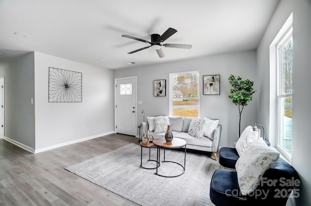 living area featuring a ceiling fan, baseboards, and wood finished floors