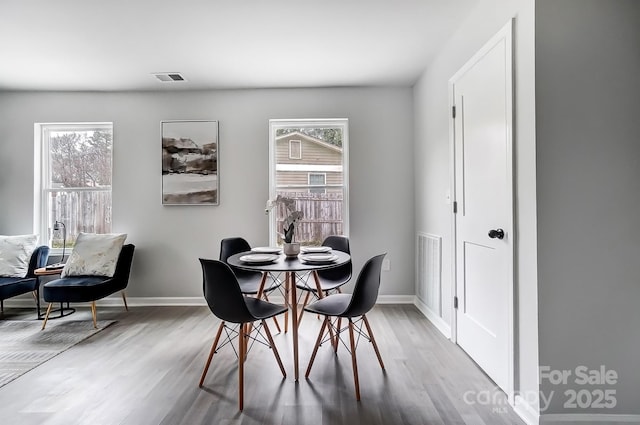 dining area featuring wood finished floors, visible vents, and baseboards