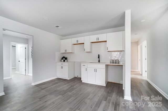 kitchen featuring dark wood-type flooring, a sink, visible vents, white cabinets, and tasteful backsplash