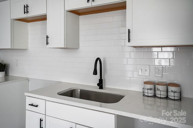 kitchen featuring white cabinets, a sink, and decorative backsplash