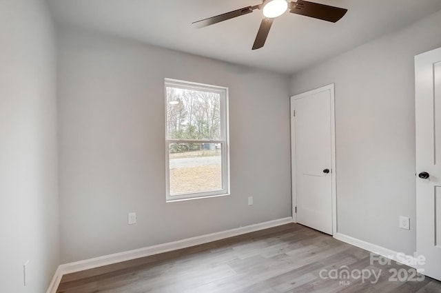 spare room featuring a ceiling fan, baseboards, and wood finished floors