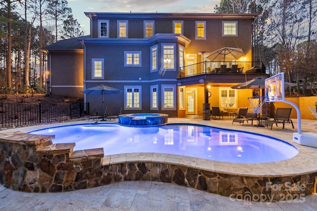 back of house featuring a pool with connected hot tub, a patio area, fence, and a balcony