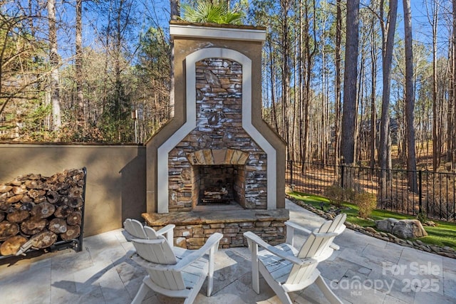 view of patio featuring fence and an outdoor stone fireplace