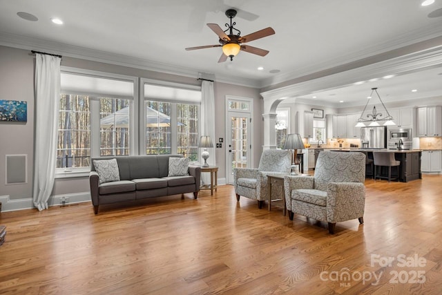 living area featuring crown molding, light wood-style floors, and ornate columns