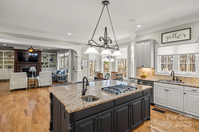 kitchen featuring appliances with stainless steel finishes, plenty of natural light, a sink, and an island with sink