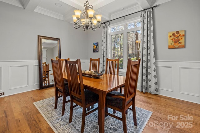 dining space featuring ornamental molding, beam ceiling, coffered ceiling, and light wood finished floors