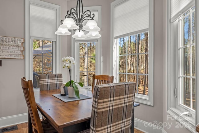 dining room featuring wood finished floors, visible vents, baseboards, and an inviting chandelier