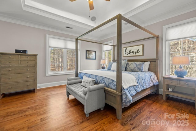 bedroom featuring a tray ceiling, visible vents, ornamental molding, wood finished floors, and baseboards