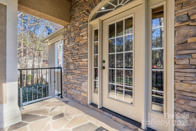 view of exterior entry with stone siding and a porch