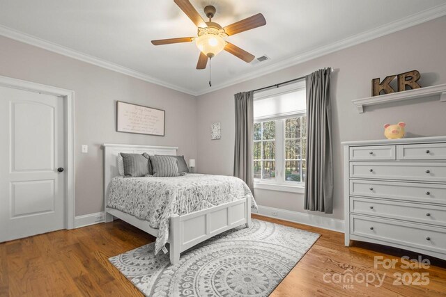 bedroom featuring ornamental molding, visible vents, and wood finished floors