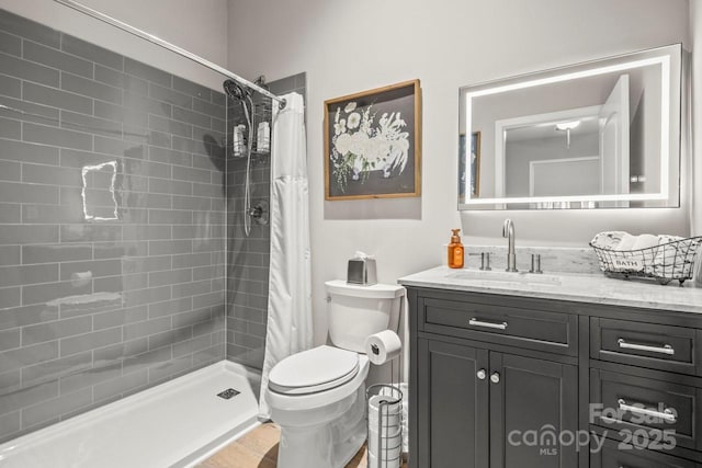 full bathroom featuring a tile shower, vanity, and toilet