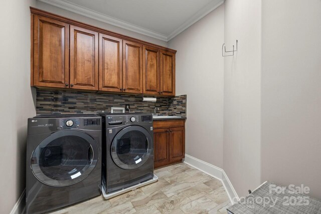 laundry room featuring a sink, baseboards, washer and dryer, ornamental molding, and cabinet space