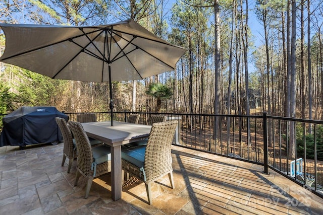 deck with outdoor dining space, a patio, and area for grilling